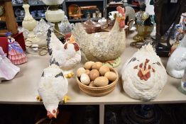 A selection of ornamental hens, lifesize and a turned bowl of wooden eggs