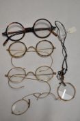 A pair of 1930s horn rimmed spectacles and similar gold tone examples.