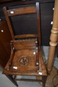 A carved oak wall sconce and a cane seated bedroom chair