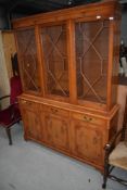 A reproduction yew wood bookcase having astral glazed display section over triple drawer and