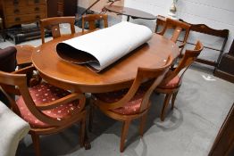 A reproduction cherry or similar extending dining table and et of six (four plus two) chairs, in