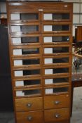 A vintage oak mid-century shopfitting / haberdashery unit having glazed panelled drawers with