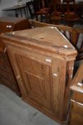 A stripped pine corner cupboard