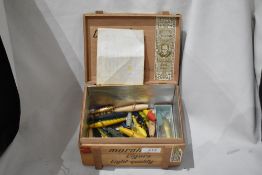 A cigar box containing a collection of wooden painted and unpainted minnows with an original bill of