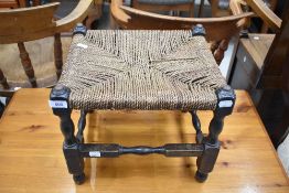 A traditional strung low stool having turned frame