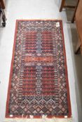A modern Turkish style rug having a red ground 135cm x 65cm, and a similar English floral rug.