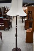 A turned and stained mahogany effect standard lamp with cream coloured shade