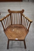 An Arts and Crafts spindle back armchair, having a shaped top rail and arms over plain spindle