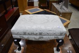 A modern footstool in the period style having cabriole legs