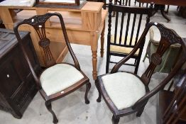 A pair of Victorian mahogany salon chairs having shaped frames and later upholstery