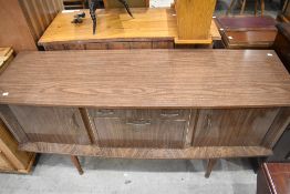 A retro mid century American walnut effect formica sideboard, of slightly bow-fronted oblong form,