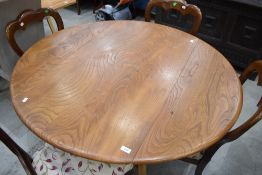 An Ercol circular dining table having drop leaves, on tapered splay legs