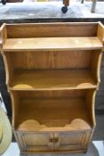 An Ercol or similar mid stained bookshelf with cupboard under, dimensions approx. W61 D35 H111cm