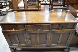 A 1940's oak sideboard, having three frieze drawers and panelled cupboards, on short turned legs