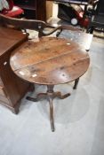 A Victorian wine table having Oak fame with circular top on tripod base with turned support.