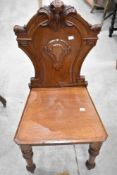 A Victorian mahogany hall chair, having a carved and moulded back over the tapering solid seat and