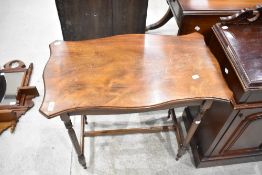 An Edwardian mahogany occasional table, having serpentine outline and slender turned spindle