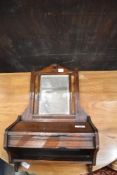 An Edwardian oak mirrored wall bracket, having sloped top lift up compartment, some repairs
