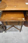 A reproduction Regency style side table having two shallow drawers on turned legs and X stretcher