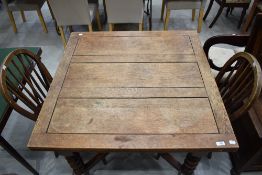 An early 20th Century oak dining table having drawer leaf and twist leg