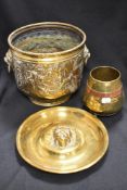 A brass coal bucket with impressed cottage scenery, a lion head wall plaque and a brass and copper