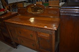 An early 20th Century oak sideboard having mirrored ledge back