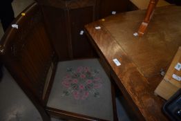 A mid 20th Century oak drawer leaf dining table and set of four chairs having woolwork seats