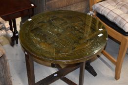 A Oriental style carved occasional table having folding frame and glass top