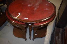 A reproduction coffee table , with quadruple nest below, all having red skiver tops and classical