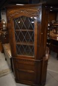 A mid to late 20th Century oak corner display having cupboard under, in the Priory style