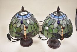 A pair of Tiffany style table lamps having dragon fly decoration to green and blue glass shade.