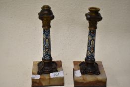 two Victorian gilt bronze and Champleve enamel columns, each resting on onyx bases.