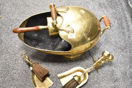 A vintage brass helmet form coal scuttle with integrated shovel and two companion sets.