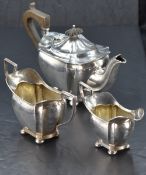 A George V silver bachelors teaset, comprising teapot, sugar and cream, of rounded rectangular