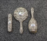 A Queen Elizabeth II silver mounted three-piece brush set, comprising hand mirror, hair brush and