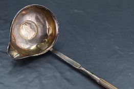 A George III white metal and baleen toddy ladle, of traditional for with twisted stem and spouted