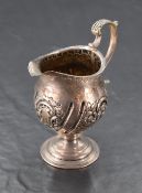 A late Victorian silver cream jug, of helmet form with bands of embossed foliate decoration, marks