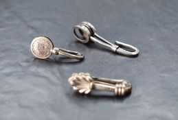 A group of three silver napkin clips/holders, each of traditional form and bearing English