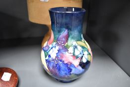 An early 20th century Moorcroft pottery vase in the Orchid pattern on blue ground with blue