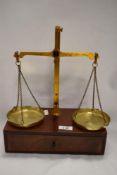 An early 20th century chemist or apothecary class B scale set mounted on mahogany draw with weight