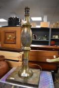 An antiqued Arts and Crafts styled lamp base in brass on a large square base. 50cm tall aprox.