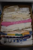 A box full of vintage and antique table linen, amongst which are embroidered examples, colourful