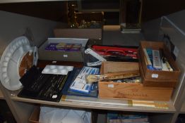 A shelf full of assorted arts and crafts materials including Humbrol paints, artist bin, geometry