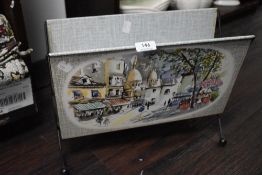 A mid century French magazine rack having printed street scene imagery