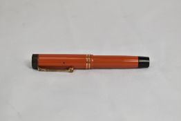 A Parker Duofold Jr Lucky Curve button fill fountain pen in coral red with two bands to cap having