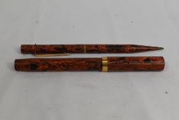 A lever fill fountain pen and propelling pencil in red and black ripple with broad band to