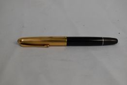 An Aurora twist fill fountain pen in black with transparent section to barrel with gold cap.