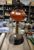 Alate Victorian oil lamp with chimney, having burnt orange glass reservoir, embossed brass column