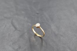An 18ct gold and platinum set single-stone opal ring, the small oval opal within a beaded setting,