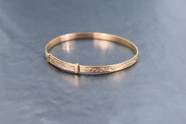 A 9ct rose gold slide clasp bangle of slim form having engraved decoration, approx 7.6g